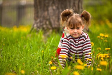 beş yıllık otların arasında oturan kız.