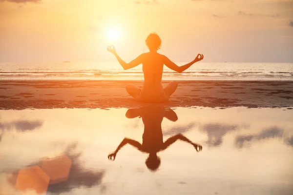 Yoga kvinna som sitter i lotus pose på stranden — Stockfoto