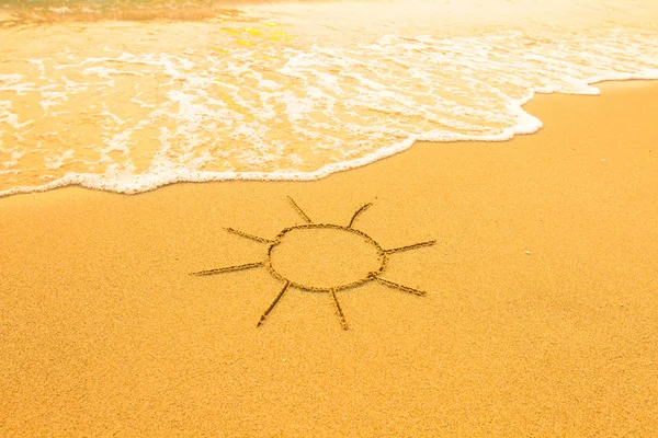 Soleil dessiné dans le sable d'une plage, vague de surf douce . — Photo