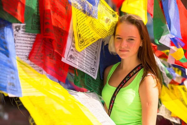 Young girl and Buddhist prayer flags flying in the Buddhist monastery. — Stock Photo, Image