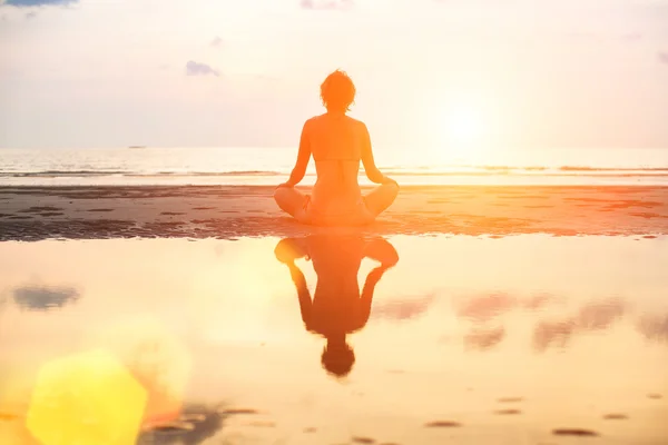 Mujer de yoga sentada en pose de loto en la playa —  Fotos de Stock