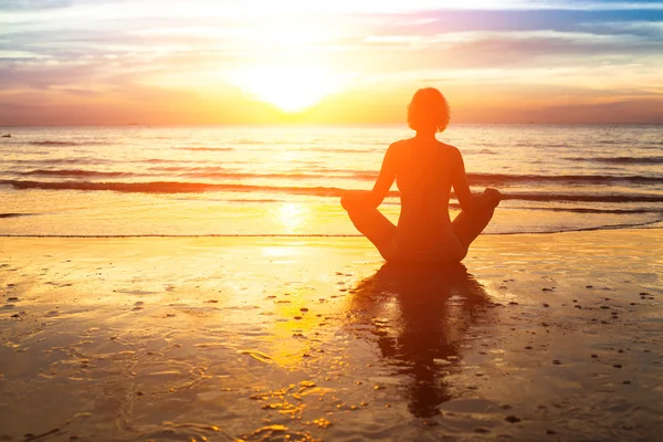 Silueta de mujer practicando yoga en la playa —  Fotos de Stock