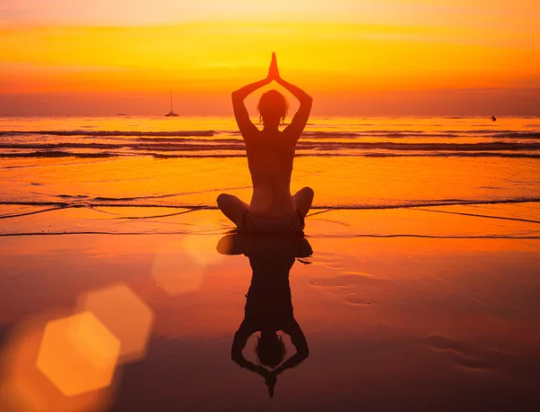 Mujer de yoga sentada en la costa del mar al atardecer . —  Fotos de Stock