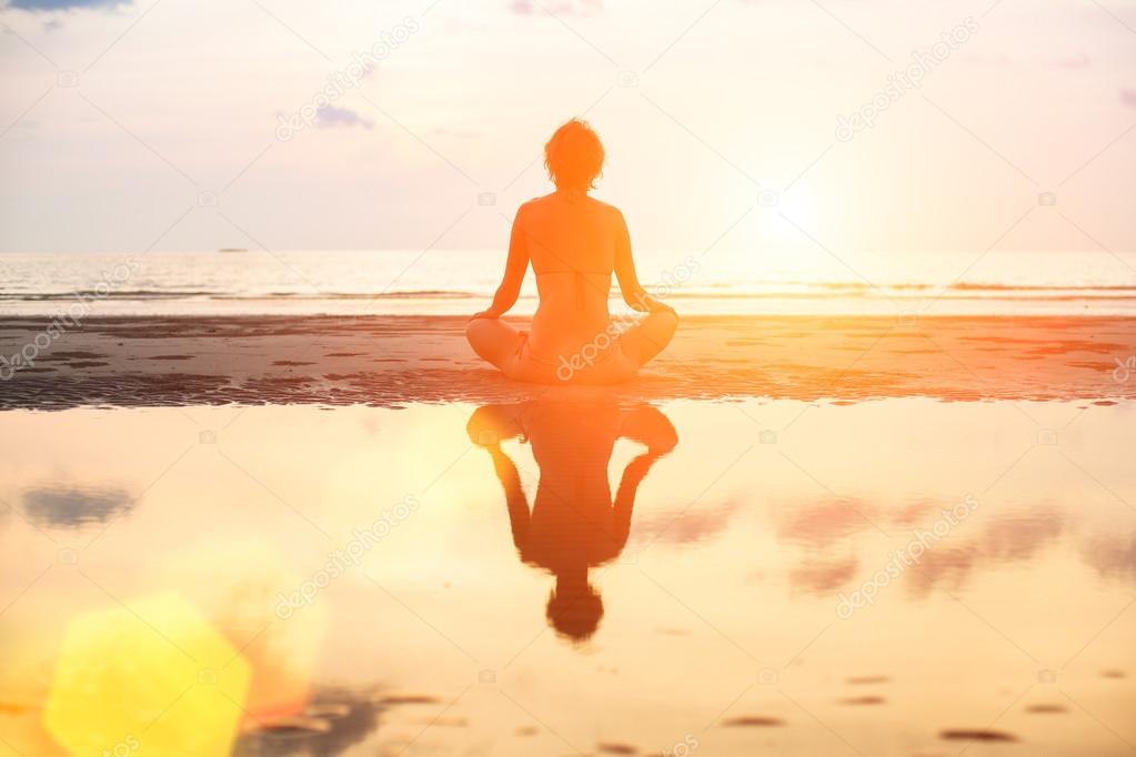 Yoga woman sitting in lotus pose on the beach