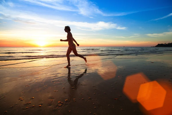 浜辺の日没で若い女性のジョガーのシルエット. — ストック写真