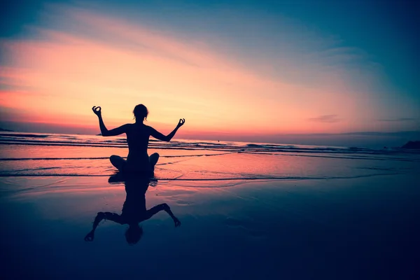 Yoga vrouw zittend op Zeekust Stockfoto