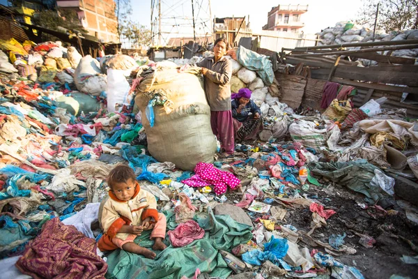 Child is sitting while her parents are working on dump — Stock Photo, Image