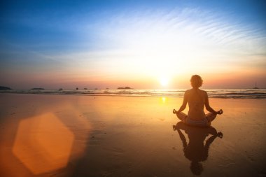 deniz üzerinde oturan yoga kadın