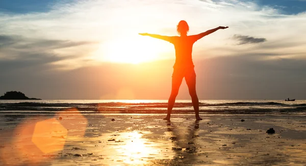 Vrouw silhouet doen oefening op het strand — Stockfoto