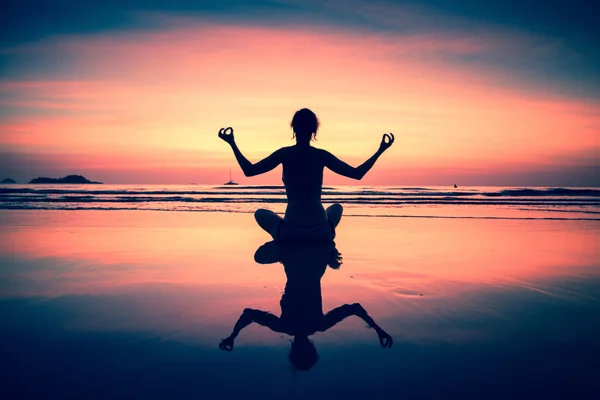Mulher de ioga sentada na costa do mar ao pôr do sol surreal . — Fotografia de Stock