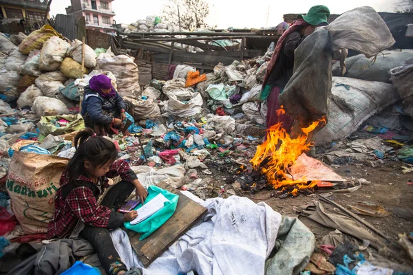 Unidentified child is sitting while her parents are working on dump — Stock Photo, Image