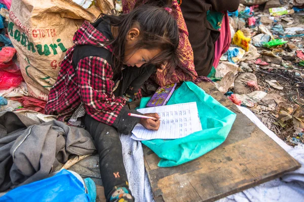 Unidentified child is sitting while her parents are working on dump — Stock Photo, Image