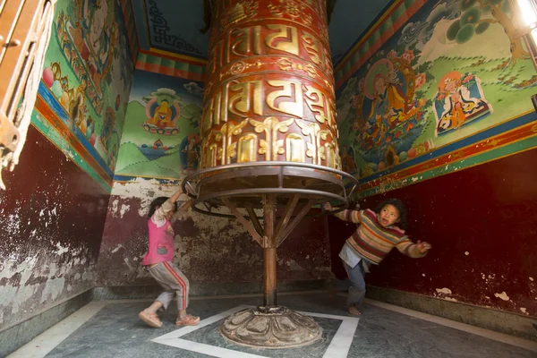 Les enfants s'amusent avec la grande roue de prière bouddhiste tibétaine qui tourne — Photo