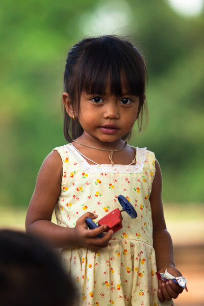 Неопознанный бедный ребенок позирует для туристов возле Ангкор-Вата
