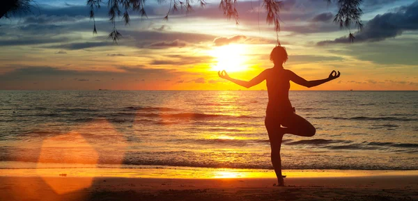 Yoga menina na praia durante o pôr do sol . — Fotografia de Stock