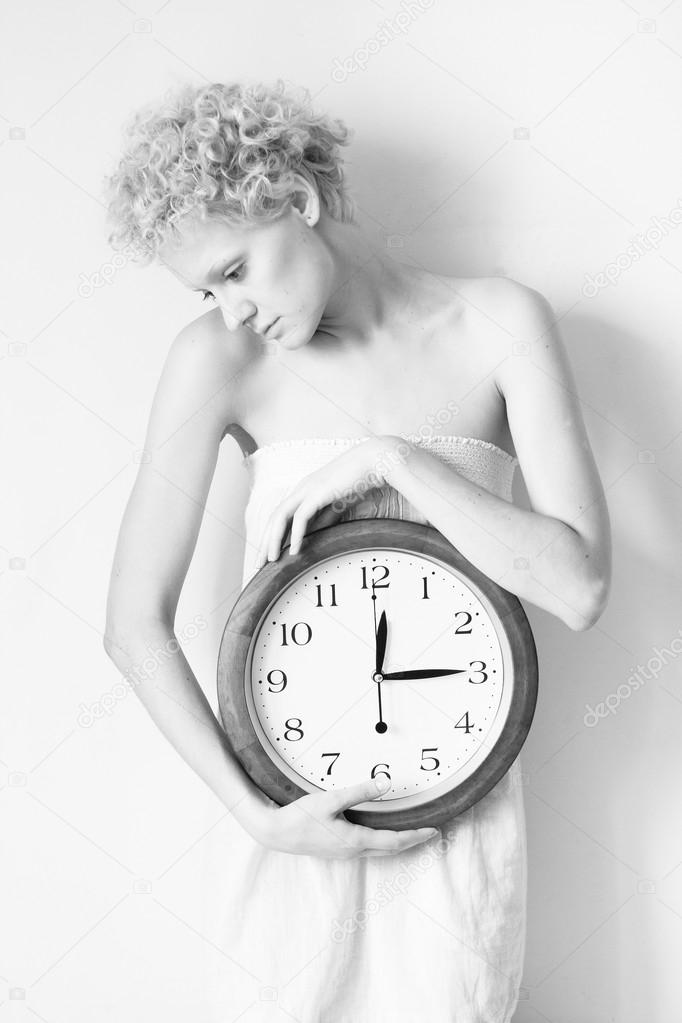 Young scrawny woman with big clock in hands