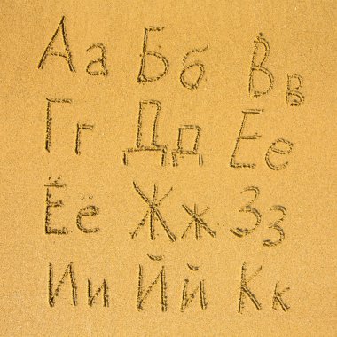 bir kum plajı üzerinde yazılı Rus alfabesi