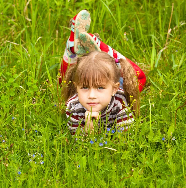 Söt liten flicka liggande på grönt gräs — Stockfoto