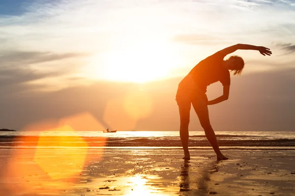 Woman Silhouette exercises on beach — Stock Photo, Image