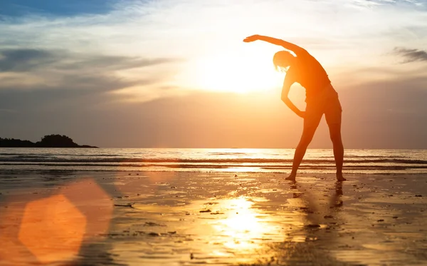 Vrouw silhouet oefeningen op strand — Stockfoto