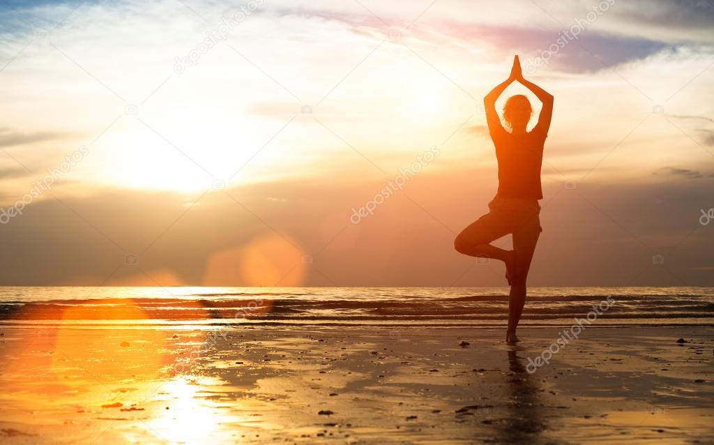 Woman practicing yoga on the beach