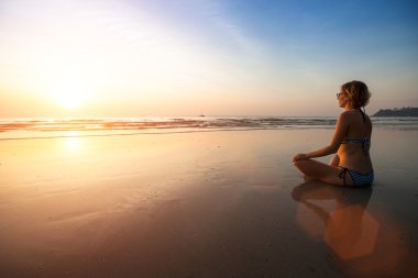 Deniz kıyısında oturan yoga kadın