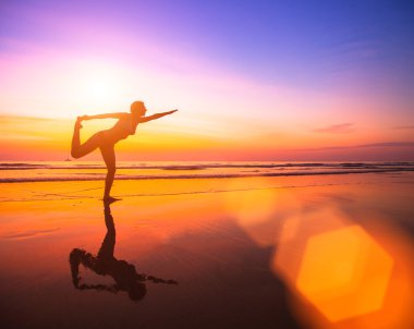 Kadın plajda yoga yapıyor.