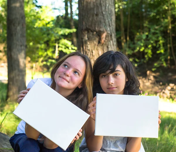 Две девушки держат чистую белую бумагу — стоковое фото