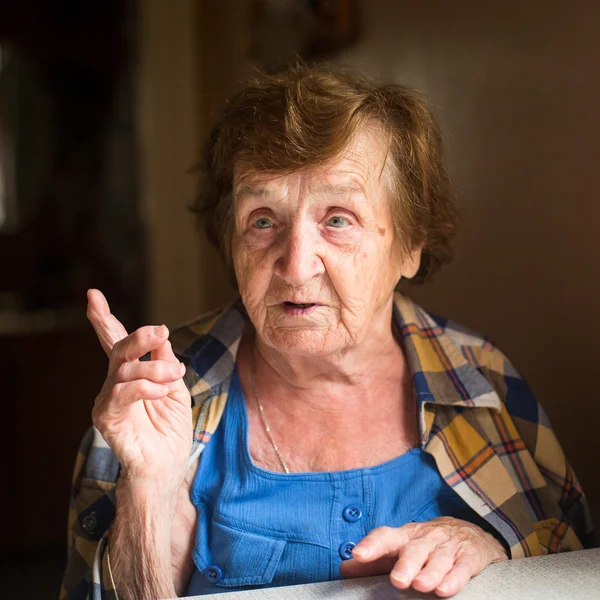 Стара жінка сидить за столом — стокове фото
