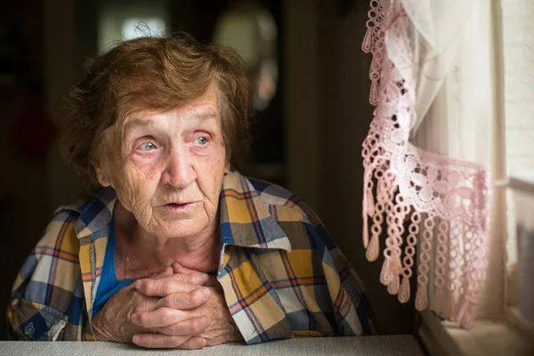 Ältere Frau schaut aus dem Fenster. — Stockfoto