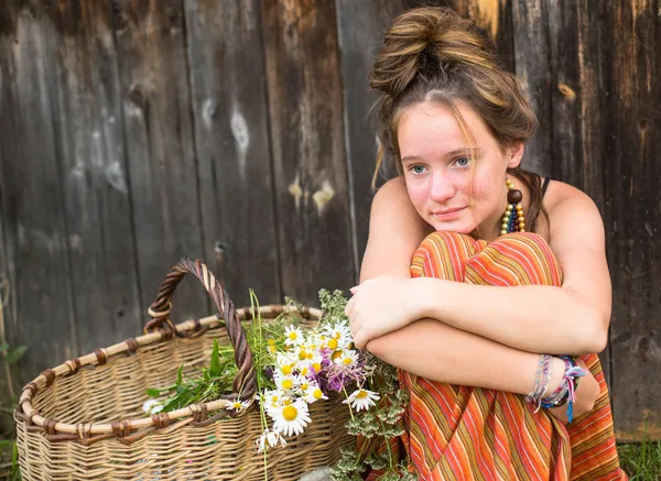 Meisje met wilde bloemen in mand — Stockfoto