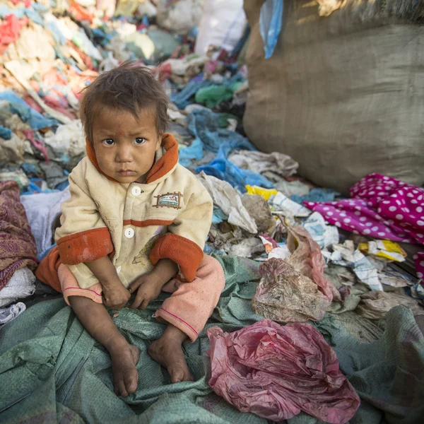 Niño está sentado en el vertedero —  Fotos de Stock