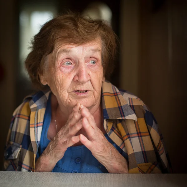 Old woman sitting at table — Stock Photo, Image