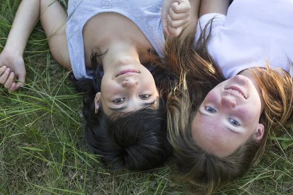 两个年轻的女孩躺在草地上. — 图库照片
