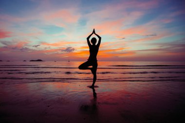 Yoga yapan kadının silueti okyanus kıyısında meditasyon yapıyor.. 