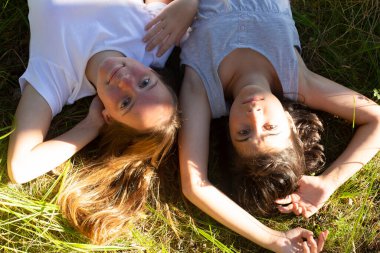 Yaz parkında yeşil çimlerin üzerinde yatan iki genç kızın portresi..