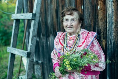 Rus köyünde etnik kıyafetler giymiş yaşlı bir kadının portresi.. 
