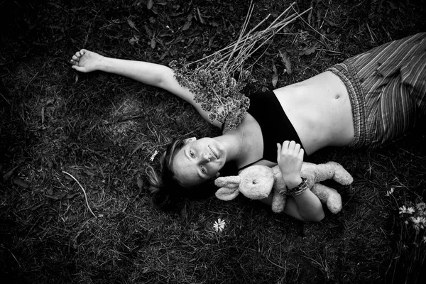 一个可爱的女孩躺在外面玩一个小孩子的玩具 黑白照片 — 图库照片