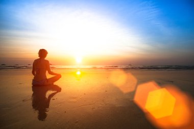 Deniz kıyısında oturan yoga kadın