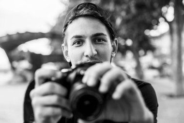 Dışarıda fotoğraf makinesi olan yakışıklı, duygusal bir adam. Siyah beyaz fotoğraf.