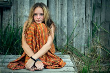 Hippi elbiseli genç kız köylerin dışında oturuyor..