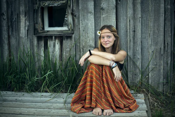 一个穿着嬉皮士衣服的女孩坐在村外 — 图库照片