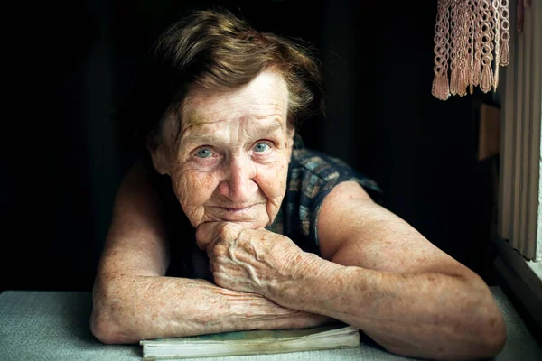 一个老妇人坐在房子桌子边的画像 — 图库照片