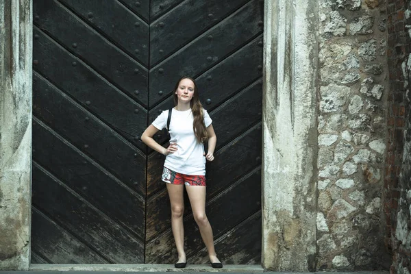 Genç Bir Kız Kocaman Ahşap Bir Kapının Yanında Duruyor — Stok fotoğraf