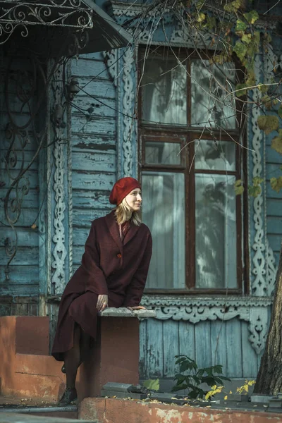 Eine Frau Weinrotem Mantel Und Baskenmütze Sitzt Auf Der Veranda — Stockfoto