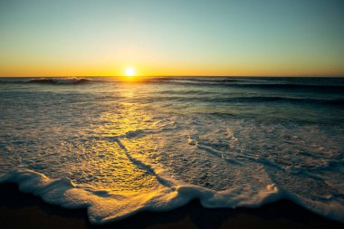 Atlantik kıyısında köpüklü sörfle güzel bir gün batımı.