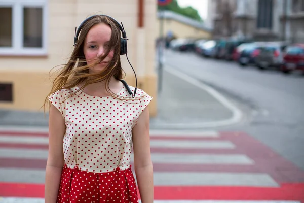 道端にヘッドフォンをしている10代の女の子が立っている ロイヤリティフリーのストック写真