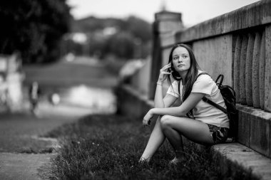 Parkta otururken cep telefonuyla konuşan tatlı bir kız..