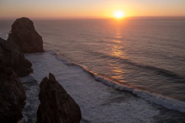 Atlantik Okyanusu 'ndaki kayalıkların ve sörfün şaşırtıcı manzarası alacakaranlıkta, Portekiz. 