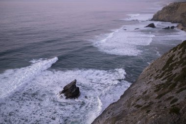 Portekiz 'in Atlantik kıyısındaki ünlü Cabo Da Roca yakınlarındaki altın gün batımında kayalıkların ve kayaların manzarası.